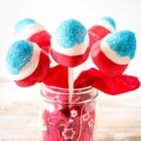 Red, white, and blue covered strawberries on sticks in a mason jar.