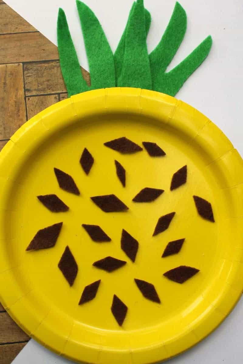 A fun and easy summer craft for kids perfect for home or school. This paper plate pineapple craft is colorful, fun, and easy to make using craft felt or paper, a paper plate, and glue.