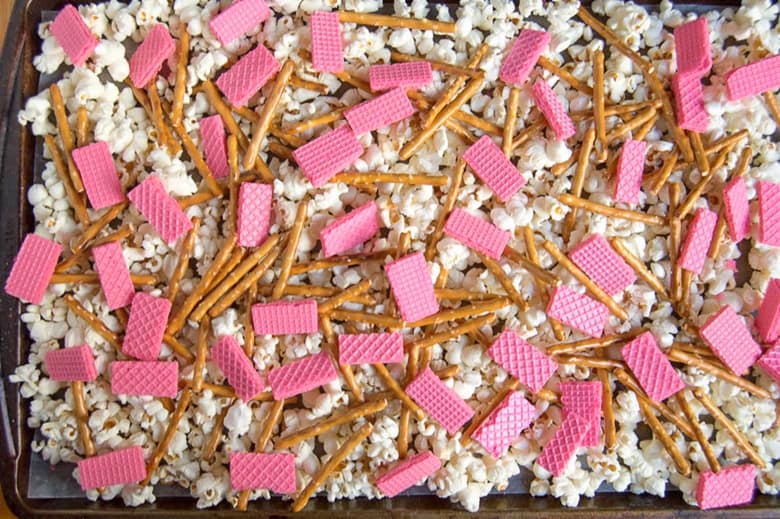 popcorn, pretzels, and strawberry wafers spread out on lined baking sheet