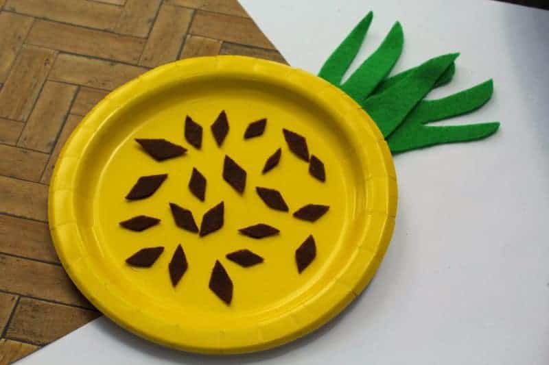 A fun and easy summer craft for kids perfect for home or school. This paper plate pineapple craft is colorful, fun, and easy to make using craft felt or paper, a paper plate, and glue.