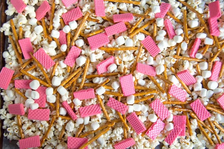 popcorn, pretzels, strawberry wafers, and mini marshmallows spread out on lined baking sheet