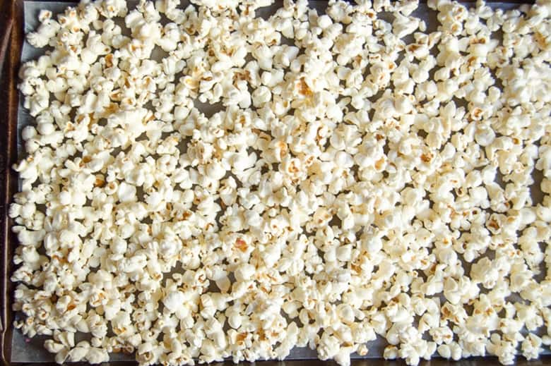 popcorn spread out on lined baking sheet