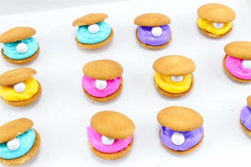 Clam shell cookies, made with vanilla wafers, icing, and candy pearls, are an easy to make no-bake treat perfect for your under the sea or mermaid party.