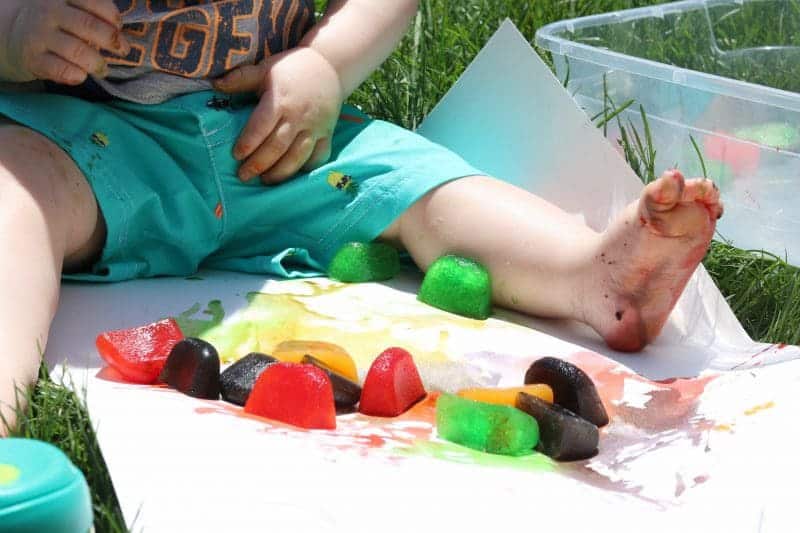 This colored ice play activity using ice cubes colored with drink mix makes for a  fun, low cost, and easy outdoor sensory activity for little ones.