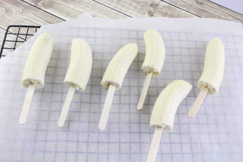 Halved bananas on popsicle sticks.