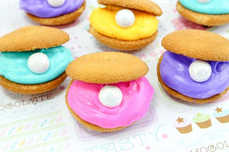 Clam shell cookies, made with vanilla wafers, icing, and candy pearls, are an easy to make no-bake treat perfect for your under the sea or mermaid party.