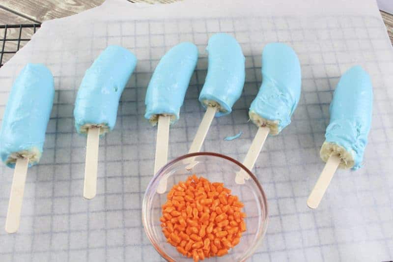 Blue coated banana pops on parchment paper.