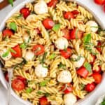 Caprese Pasta Salad with rotini pasta, mozzarella balls, fresh basil, and tomatoes in a large bowl