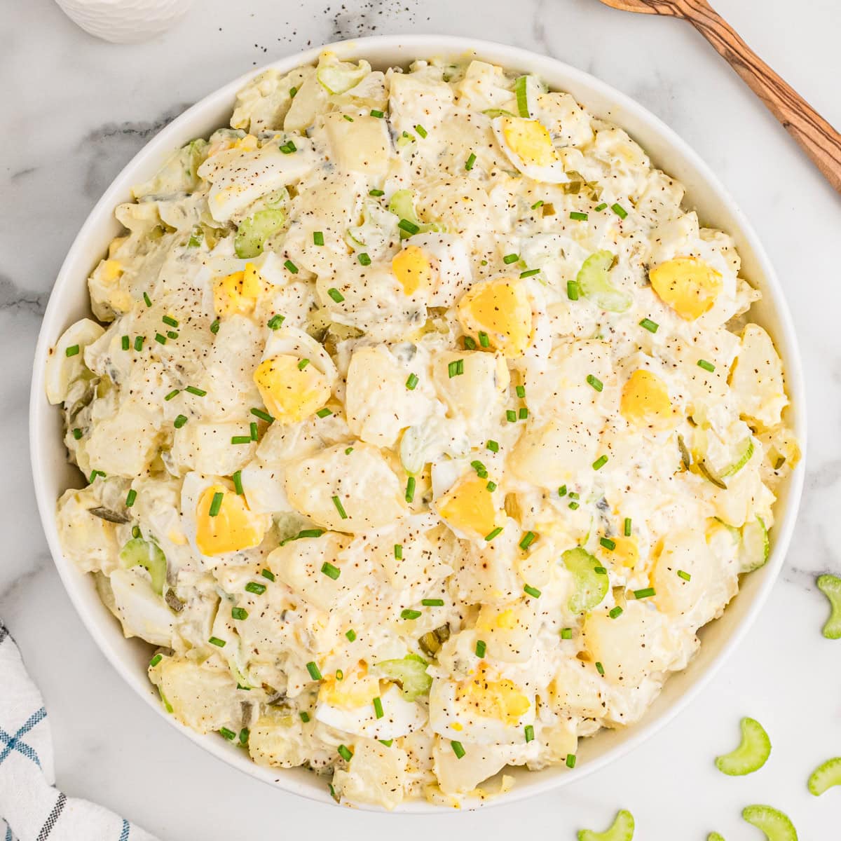 Overhead view of old fashioned potato salad with egg in a while bowl.