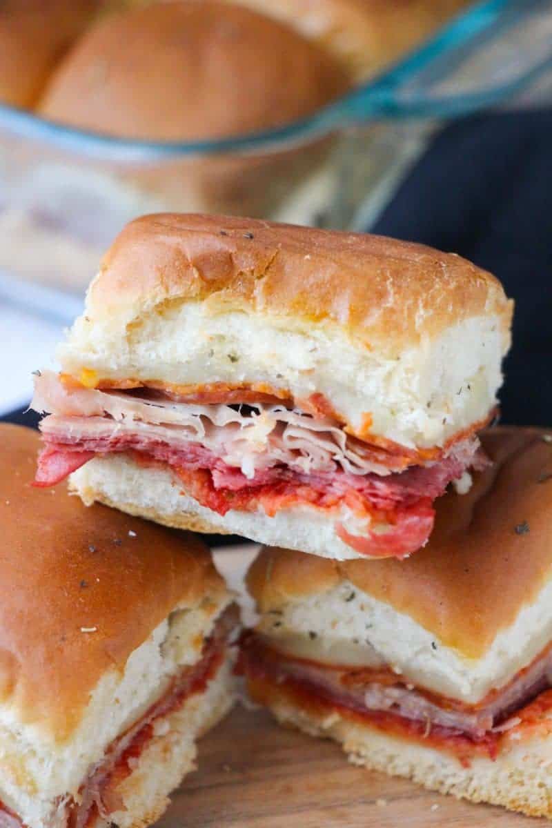 Close up image of pull-apart hot Italian sliders with ham, salami, pepperoni, and provolone cheese.