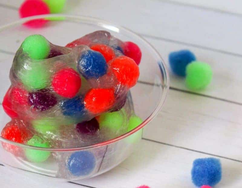 This 4-ingredient pom pom slime features brightly colored pom poms suspended in a clear slime for a bright, colorful, and fun sensory activity for kids.