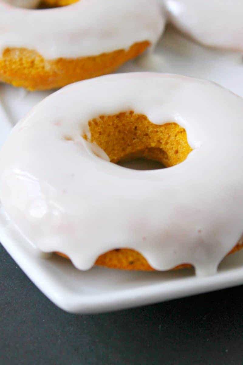 Baked pumpkin doughnuts smothered with vanilla glaze.