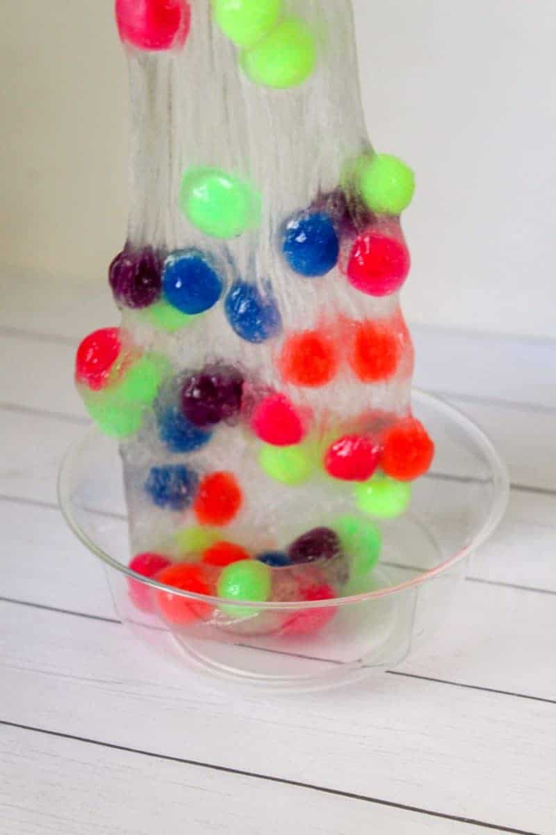 This 4-ingredient pom pom slime features brightly colored pom poms suspended in a clear slime for a bright, colorful, and fun sensory activity for kids.