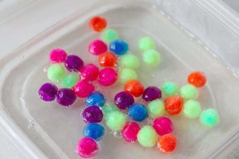 This 4-ingredient pom pom slime features brightly colored pom poms suspended in a clear slime for a bright, colorful, and fun sensory activity for kids.