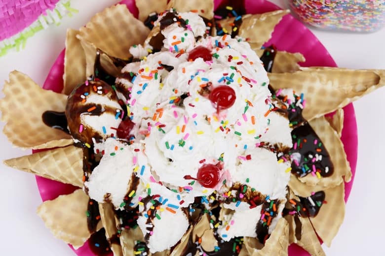 Ice cream nachos sundae with vanilla ice cream, whipped cream, sprinkles, chocolate syrup, and cherries.