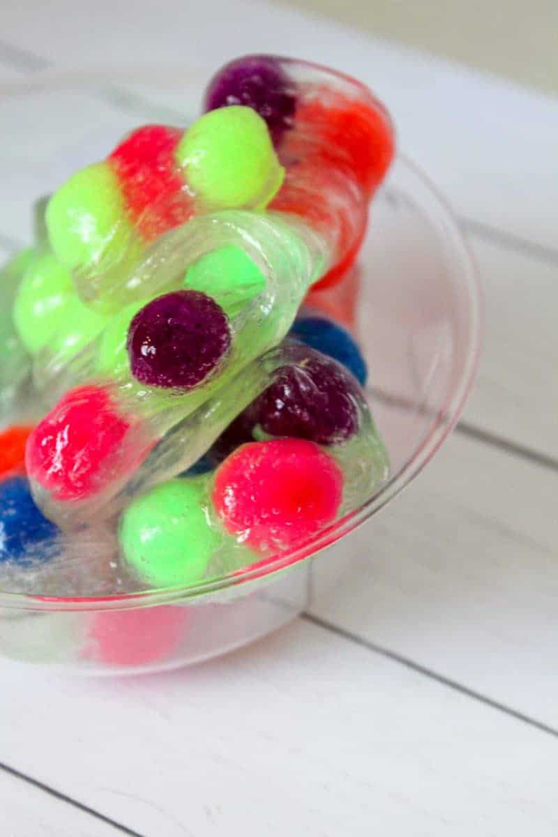 This 4-ingredient pom pom slime features brightly colored pom poms suspended in a clear slime for a bright, colorful, and fun sensory activity for kids.