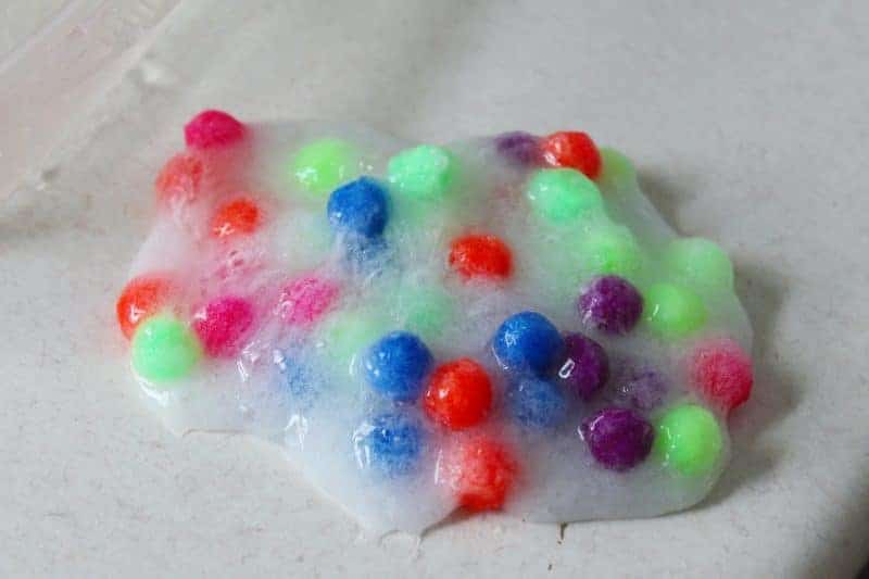 This 4-ingredient pom pom slime features brightly colored pom poms suspended in a clear slime for a bright, colorful, and fun sensory activity for kids.