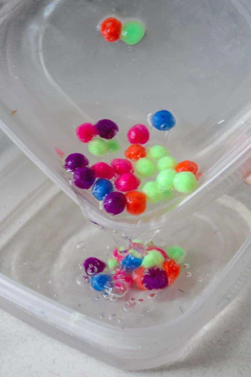 This 4-ingredient pom pom slime features brightly colored pom poms suspended in a clear slime for a bright, colorful, and fun sensory activity for kids.