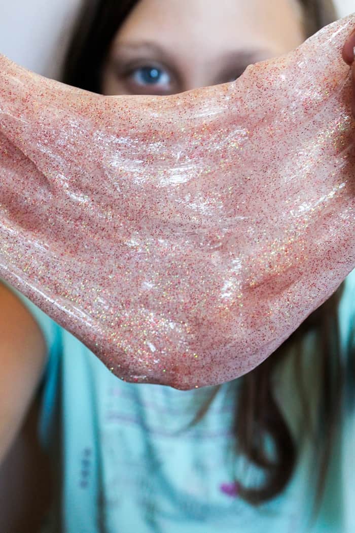 Young girl stretching out glittery fall slime.