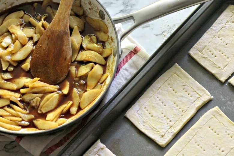 Apple filling in a pan next to tray of rectangular pieces of puff pastry 