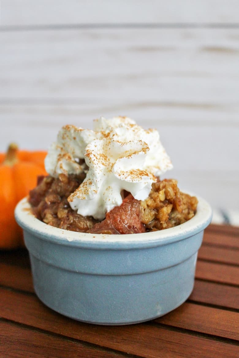 apple pear crisp served in a small bowl with whipped cream on top
