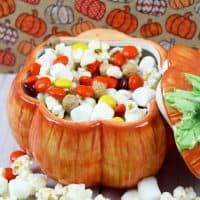 No bake fall snack mix with mini marshmallows, kettle popcorn, Reese's pieces, and Reese's Puffs Cereal served in a pumpkin shaped bowl.