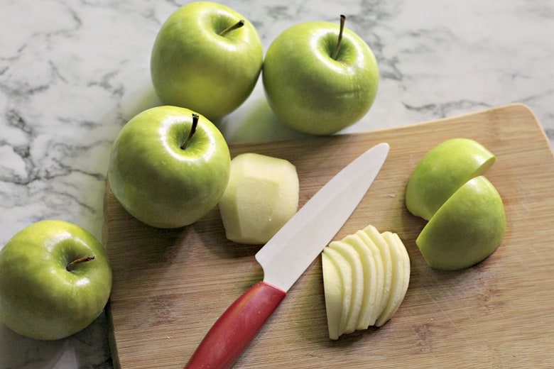 green apples being sliced on a cutting board 