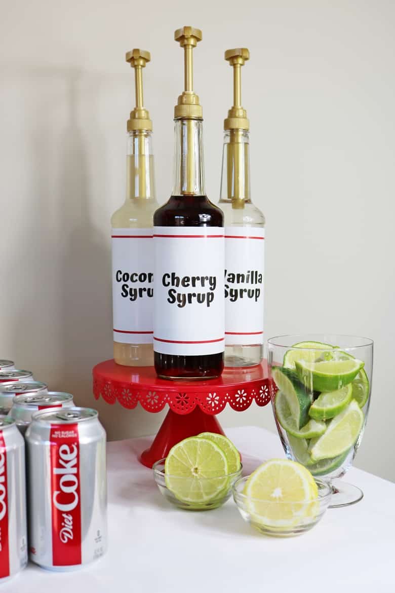 Vanilla, Coconut, and Cherry Flavored Syrups next to a bowl of limes and lemon slices