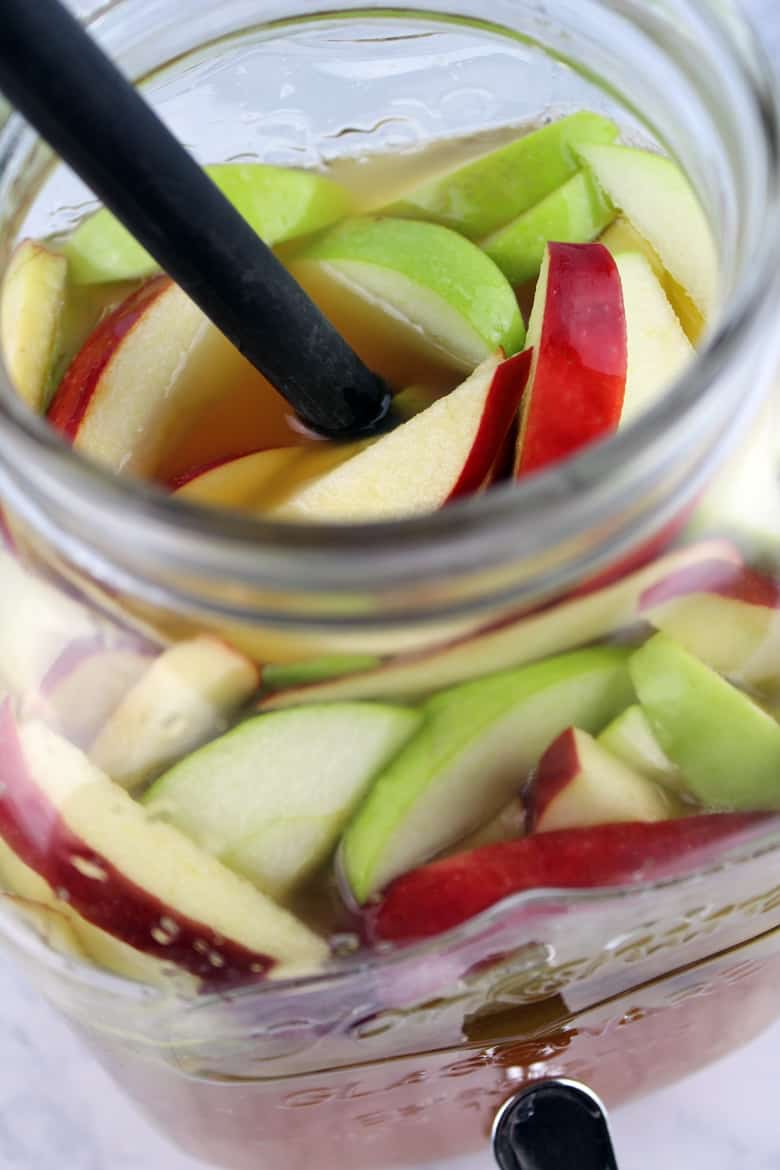Sliced apples soaking in vodka and wine to make sangria