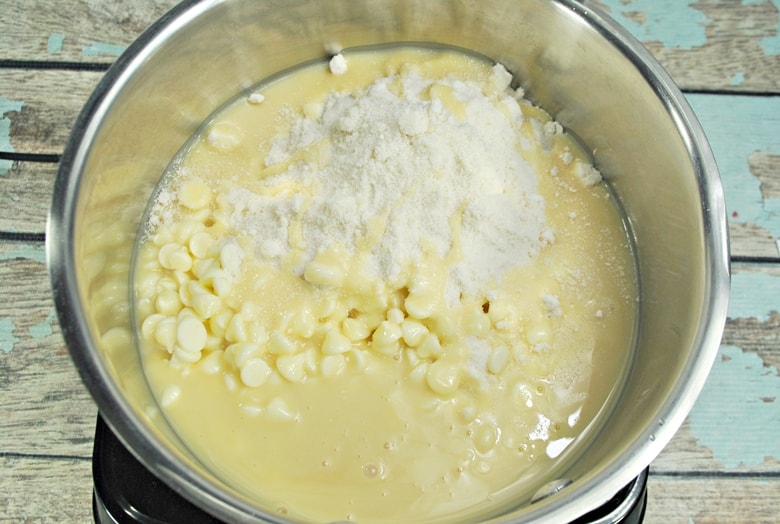 Condensed milk, sugar cookie mix, and white chocolate chips in pot