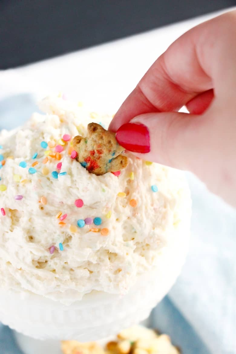 dipping a teddy graham in finished cake batter dip
