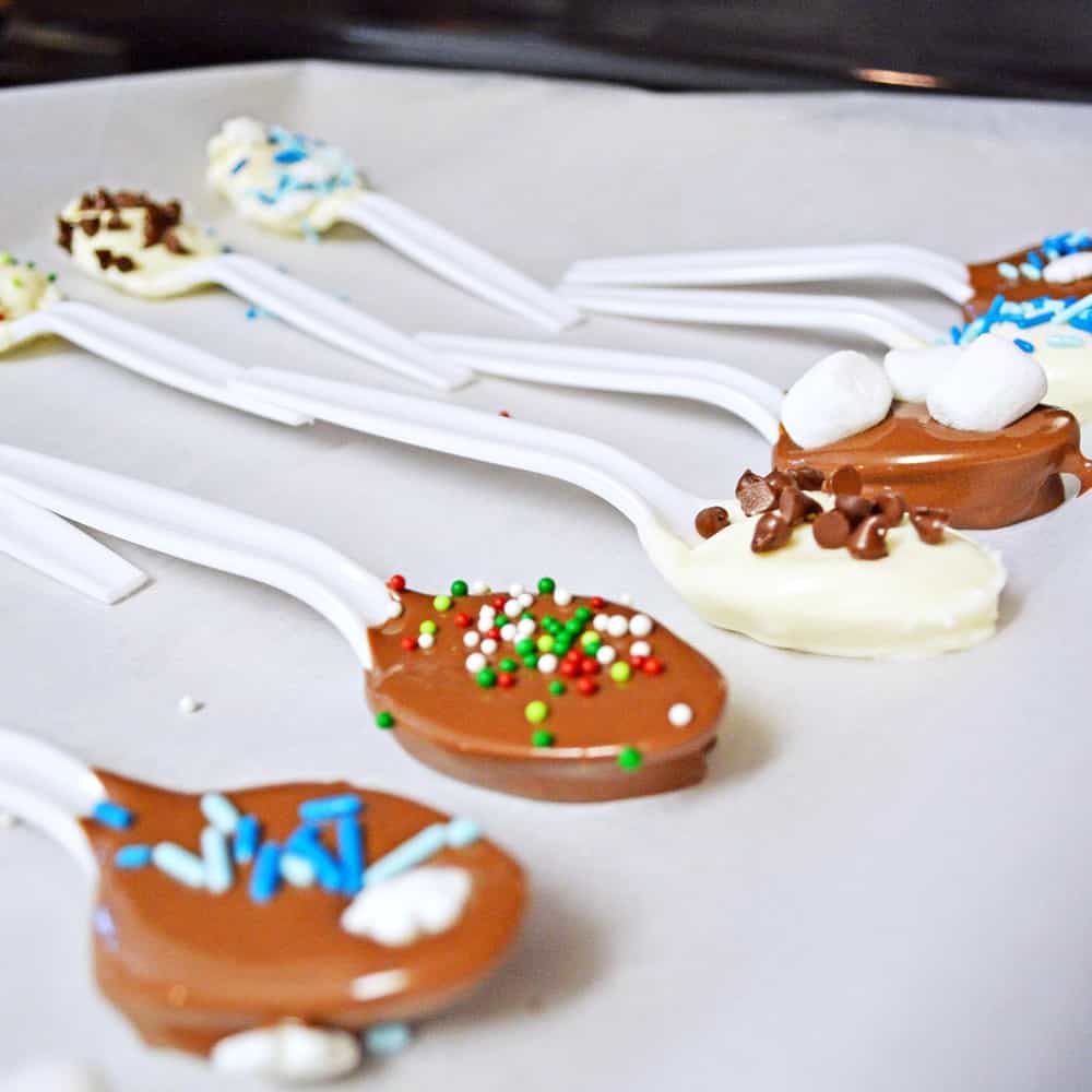 Chocolate dipped spoons setting on a parchment lined baking sheet