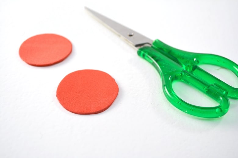 two circles of red foam next to green scissors