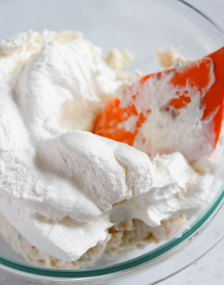 Large bowl with red spatula folding in whipped topping.