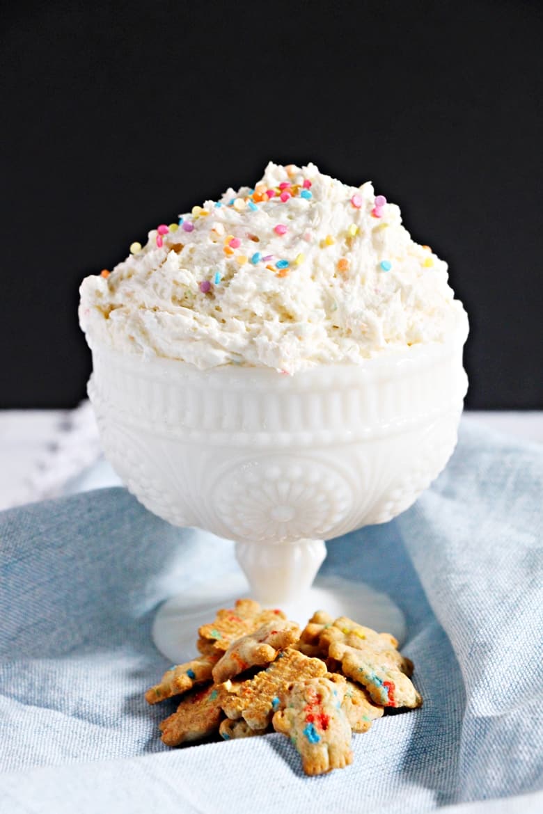 Funfetti cake batter dip served in large white bowl with teddy grahams on the side for dipping.
