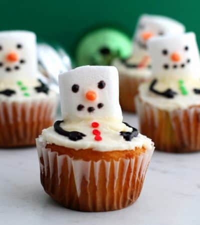 Melting snowman cupcakes are an easy to make Winter dessert made by adding a marshmallow and a few other small decorations to vanilla cupcakes.