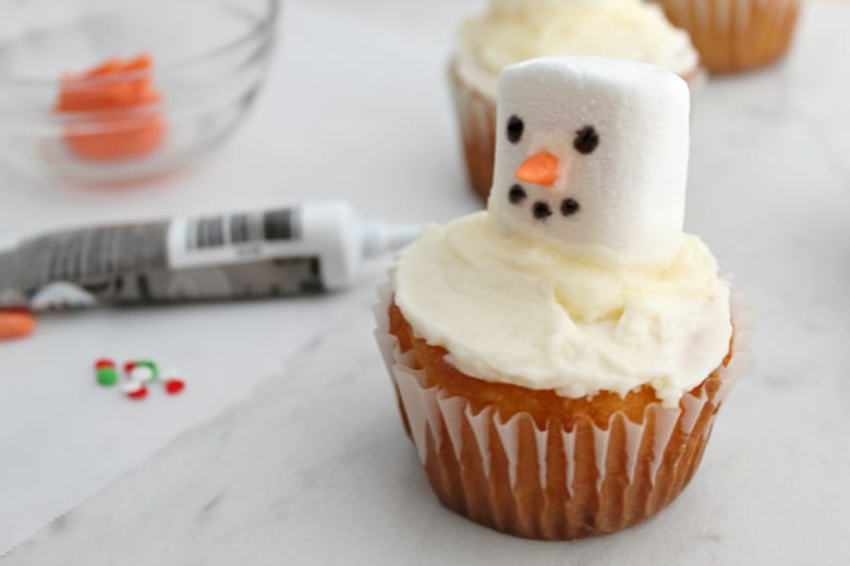 In process picture of snowman cupcake with nose, eyes and mouth completed