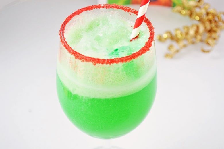 Green holiday drink in red rimmed glass.