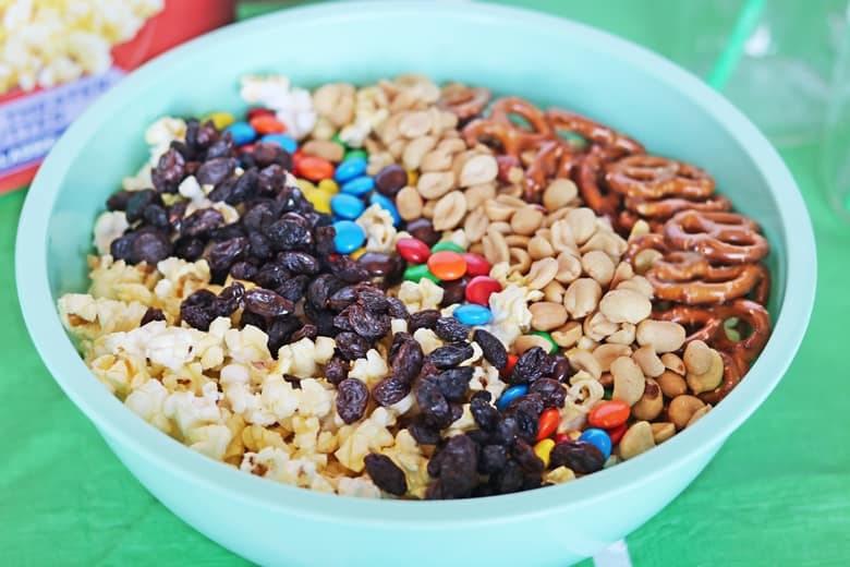 Popcorn, raisins, chocolate candies, and pretzels in a large turquoise bowl