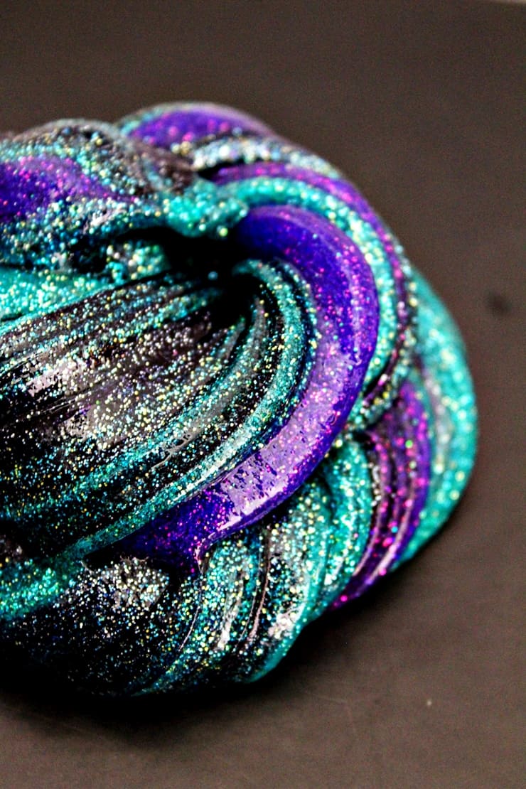Galaxy slime - a combination of black, purple, and teal glitter slimes