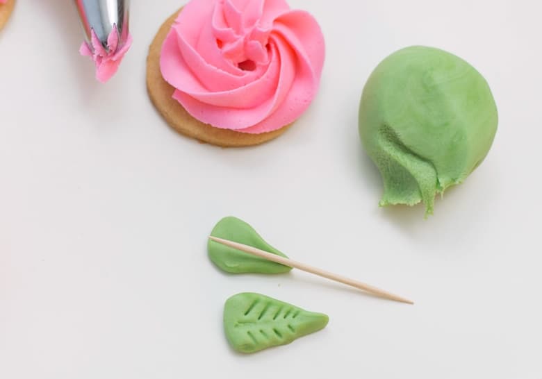 Toothpick being used to make lines on the green fondant leaves.