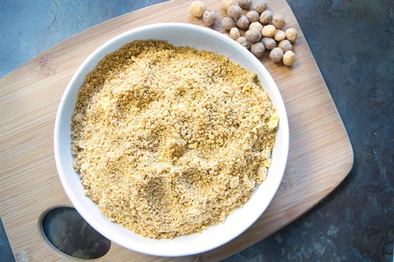 crushed Reese's Puffs cereal in a white bowl, on a wooden cutting board