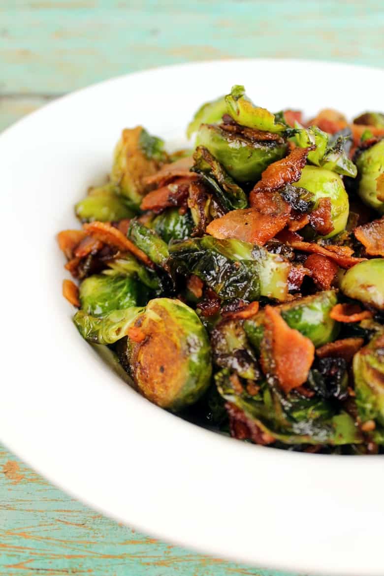 Brussel Sprouts with Bacon and Balsamic Reduction in a white bowl on a wooden table