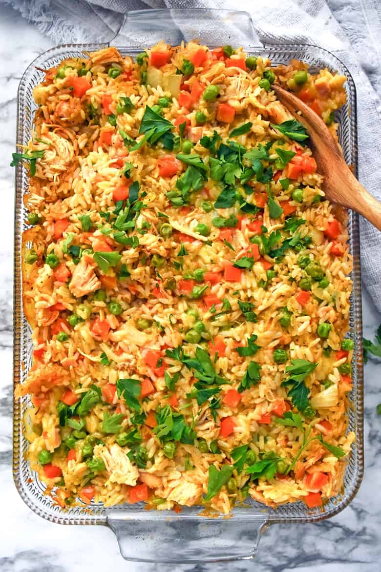 Creamy chicken and rice casserole in baking dish with wooden spoon