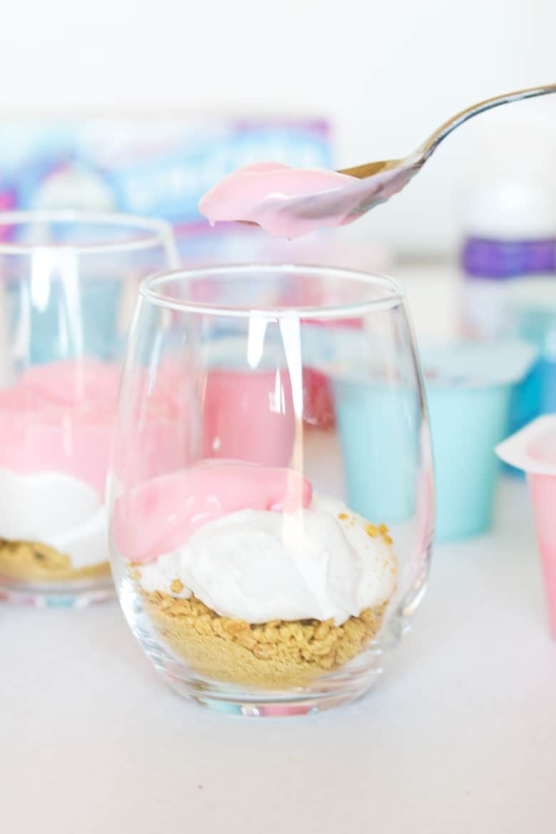 Spooning pink pudding into parfait glass.