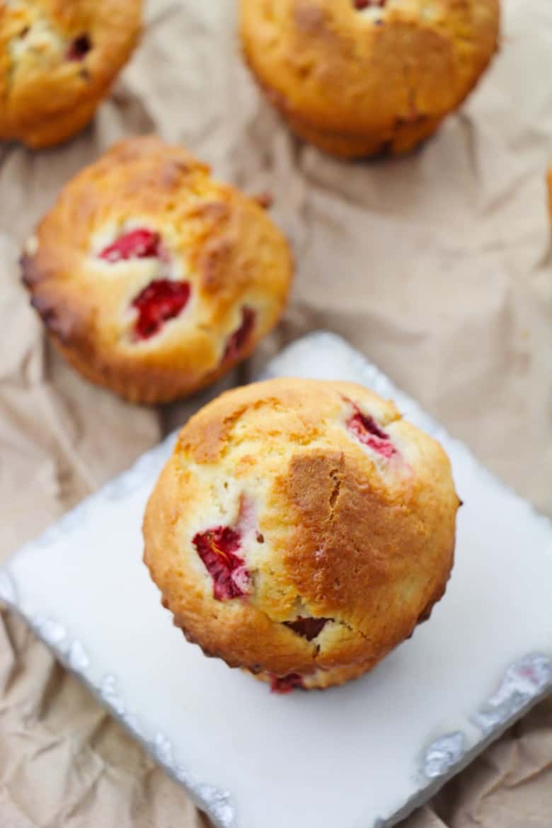 Strawberry muffin on grey slate tile, with additional muffins seen in the background