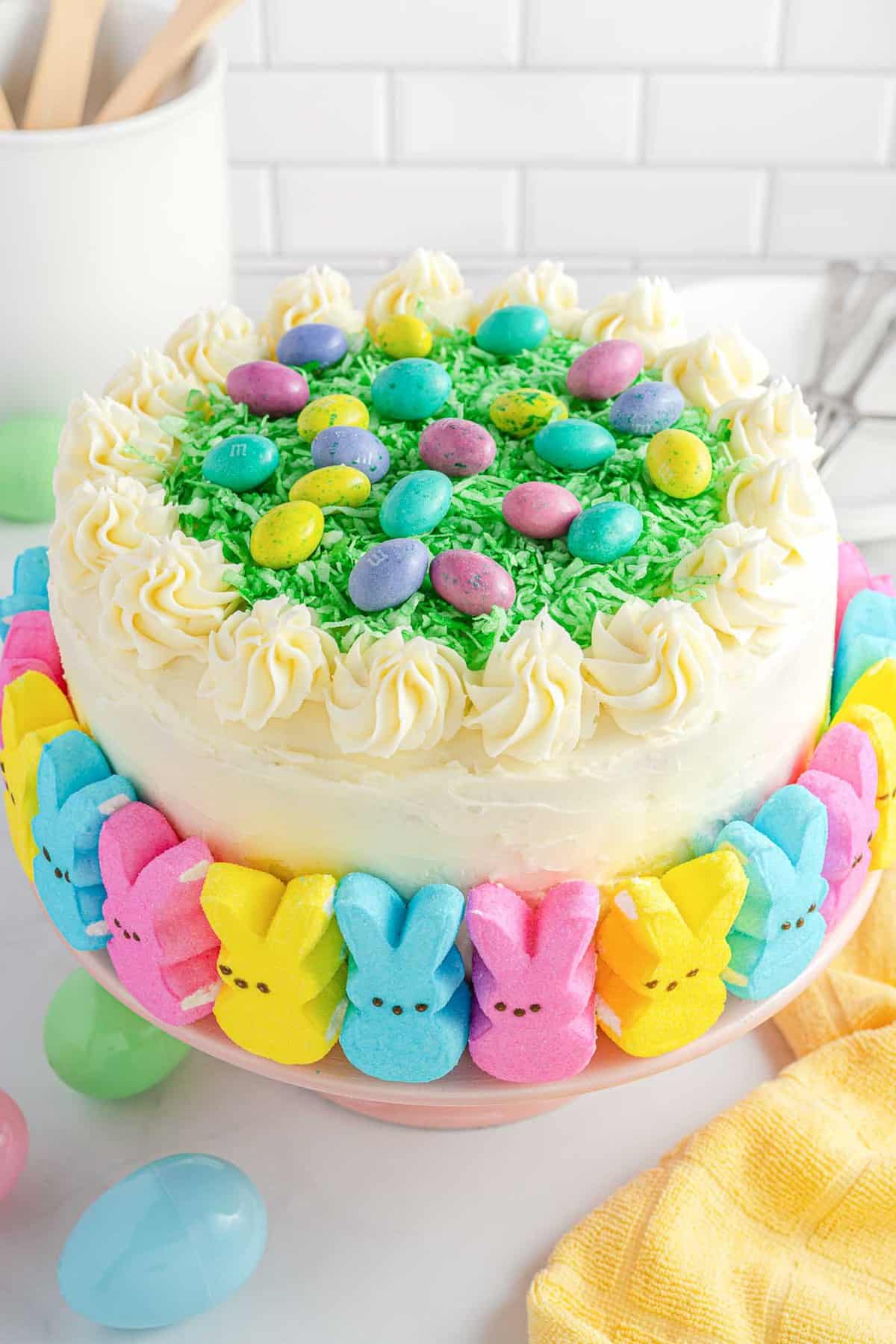 Easter Layer Cake decorated with marshmallow peeps, shredded coconut, and candy eggs.