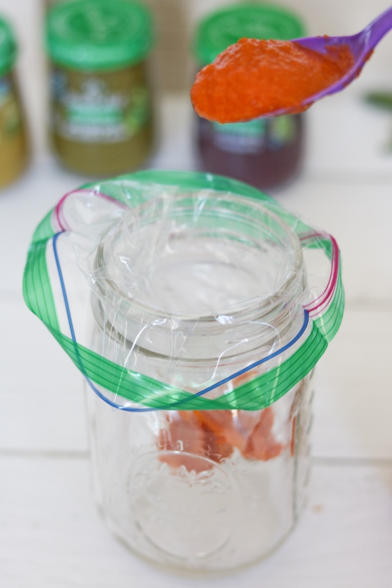 sandwich baggie in mason jar, being filled with an orange baby food puree.