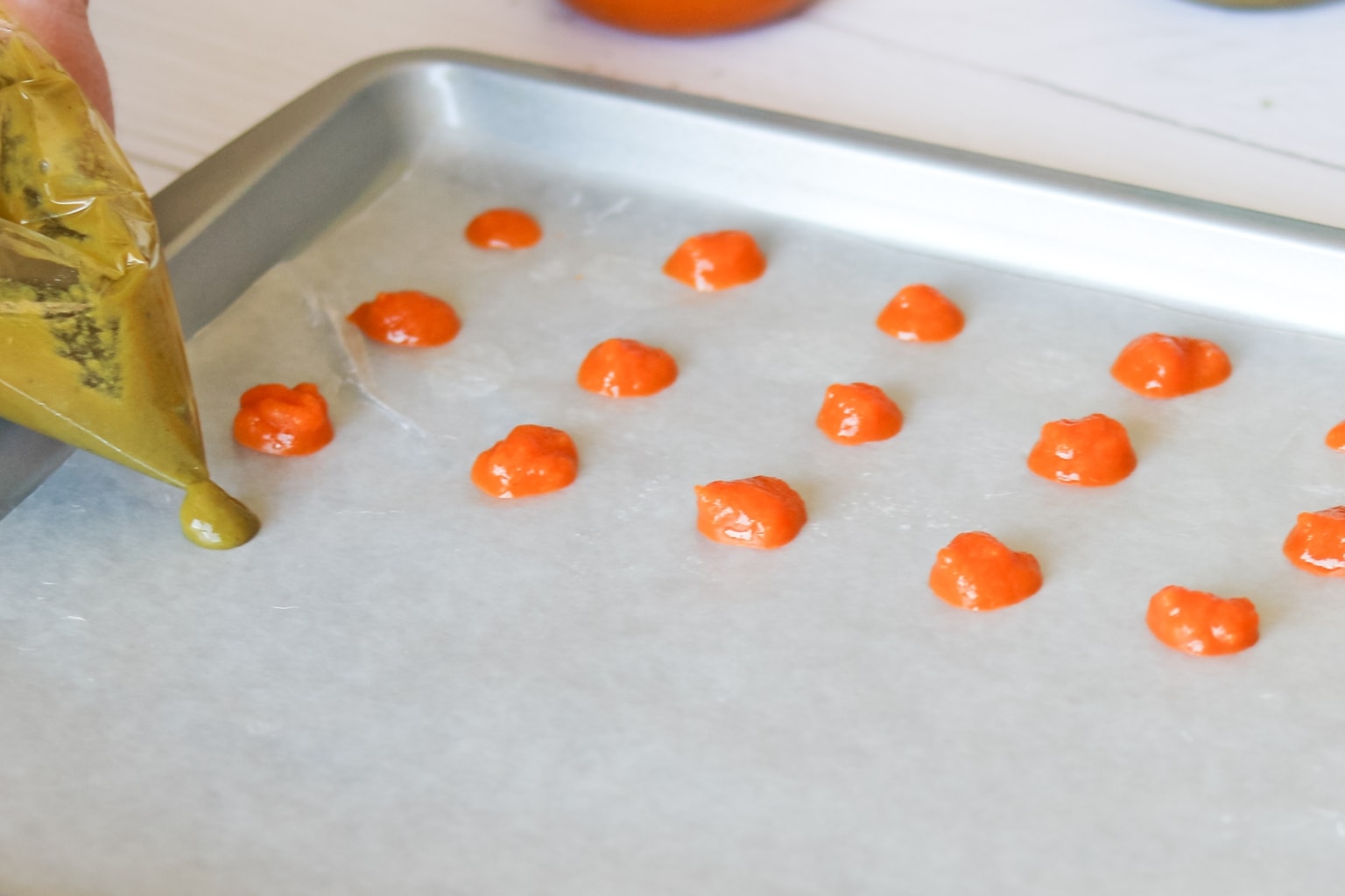 piping small dots of baby food onto lined baking sheet