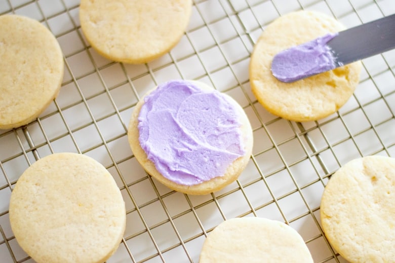 An offset spatula icing cookies on a cooling rack